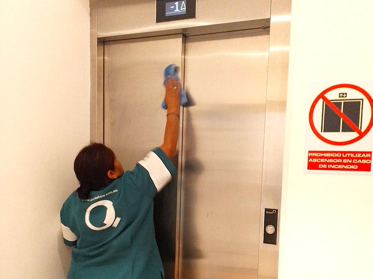 Colaboradora de Quickshine limpiando las puertas de un elevador