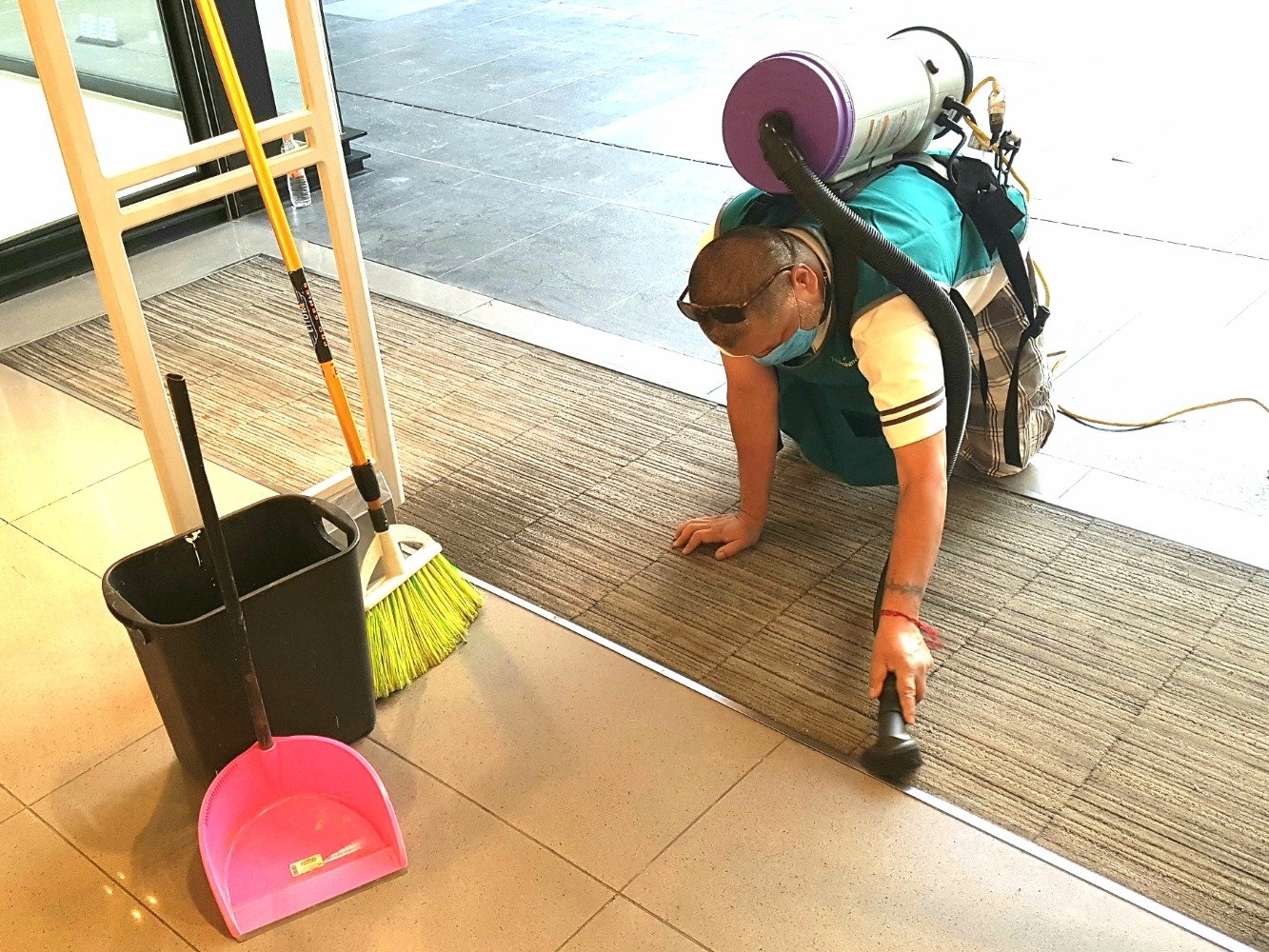 Colaborador de Quickshine aspirando un tapete de entrada con aspiradora de mochila